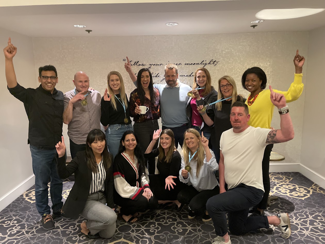 Group of participants raising their hands and celebrating after completing a mobile escape room challenge, some holding medals and small trophies